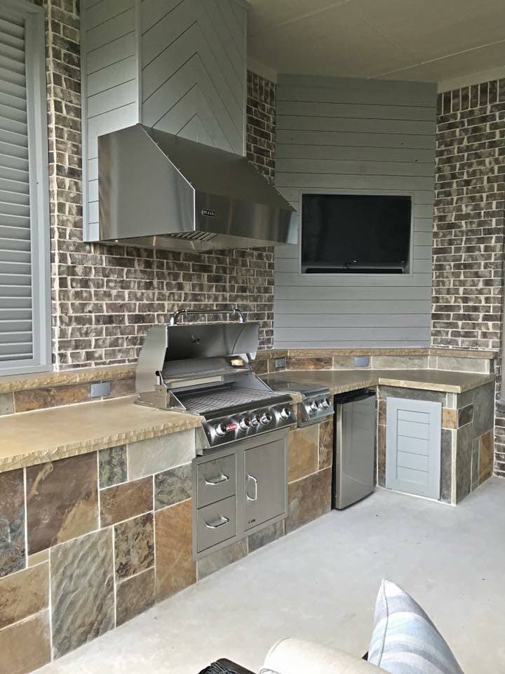 Outdoor living kitchen set in a spacious backyard in Flower Mound, Texas, 75022 featuring stainless steel appliances, stone countertops, and a built-in grill.
