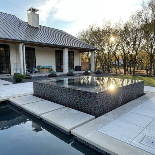 beautiful outdoor swimming pool & living space with travertine pavers and custom hot tub in Highland Village Texas