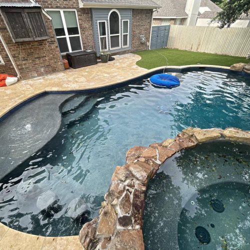 Inviting pool deck with travertine pavers in Double Oak 75077